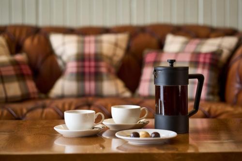 a coffee maker and two cups on a wooden table at Ulbster Arms Hotel near Thurso in Halkirk