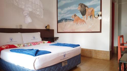 1 dormitorio con 1 cama y una foto de un león en Miryams Village Inn Safari Lodge, en Sultan Hamud