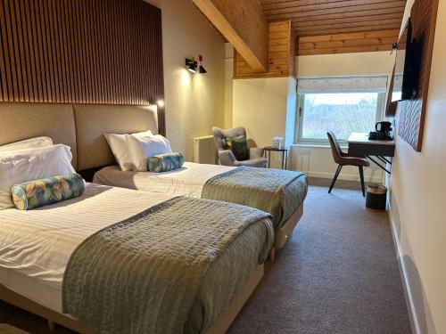 um quarto de hotel com duas camas e uma secretária em Dorset Resort Hotel em East Stoke