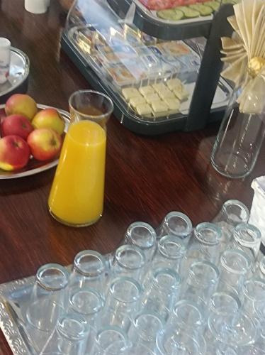 a table with glasses of orange juice and a plate of apples at Villa Zdrojowa in Otmuchów