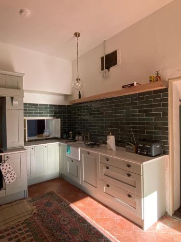 a kitchen with white cabinets and a brick wall at Ashville Georgian House in Killinchy