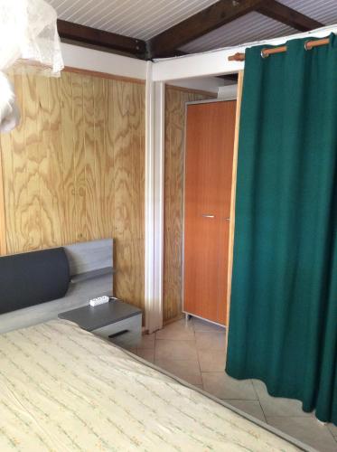 a bedroom with a bed and a green curtain at fleurs de canne in Petit-Bourg
