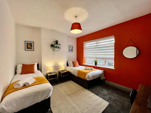 a bedroom with two beds and a red wall at Daubney House - Urban Oasis Townhouse in Cleethorpes