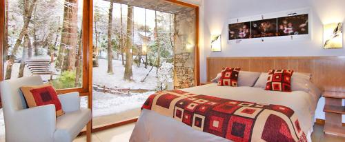 1 dormitorio con cama, ventana y silla en Kalasur Patagonia Apart Hotel en San Martín de los Andes
