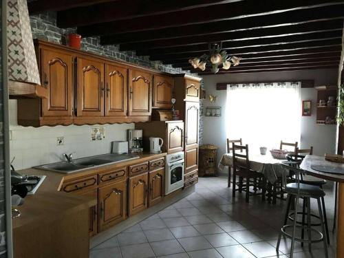 a kitchen with wooden cabinets and a table and a dining room at Le Sapin in Audrehem