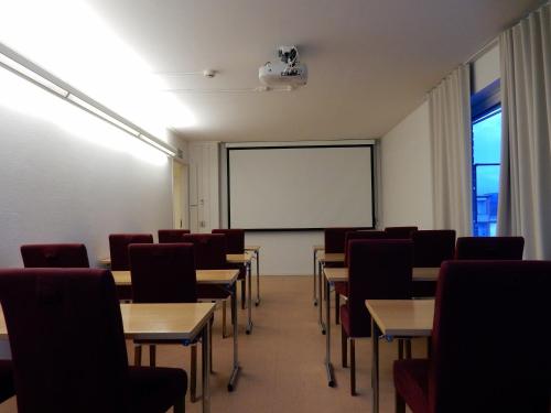 a classroom with tables and chairs and a whiteboard at Grand Hotell Bollnäs in Bollnäs