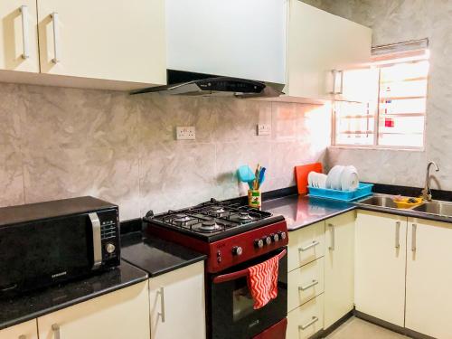 a kitchen with a stove and a microwave at Crayford Homes in Ikeja