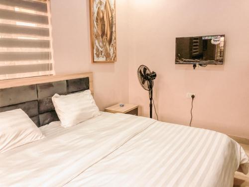 - une chambre avec un lit blanc et un ventilateur dans l'établissement Crayford Homes, à Ikeja