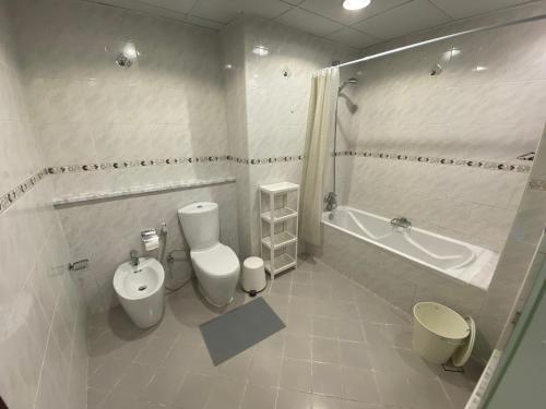 uma casa de banho com um WC, uma banheira e um lavatório. em One bedroom apartment with pool & gym near Marina em Dubai