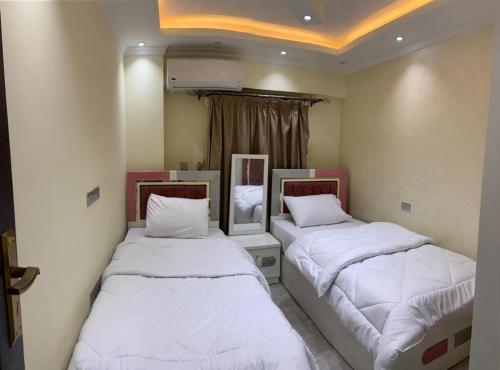 duas camas num quarto com lençóis brancos em شقة فندقية جديدة no Cairo