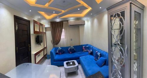 uma sala de estar com um sofá azul e uma mesa em شقة فندقية جديدة no Cairo