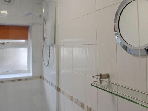 uma casa de banho com um chuveiro e um espelho. em The Little House em Conwy