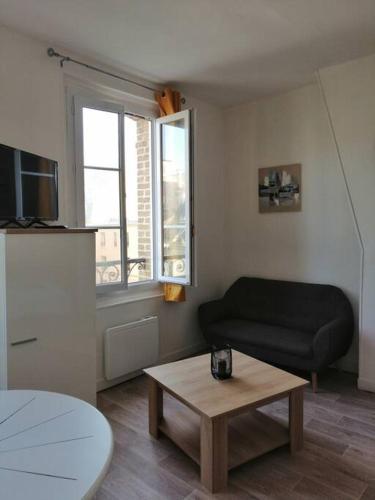 uma sala de estar com um sofá preto e uma mesa de centro em Charmant studio -Dieppe centre em Dieppe