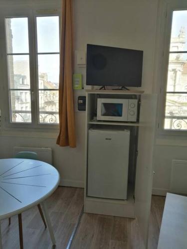 un salon avec une télévision et une table dans l'établissement Charmant studio -Dieppe centre, à Dieppe