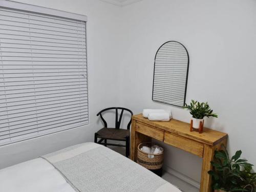 a bedroom with a bed and a mirror on a table at Cozy 2 bedroom APT - Near Kenilworth Racecourse in Cape Town