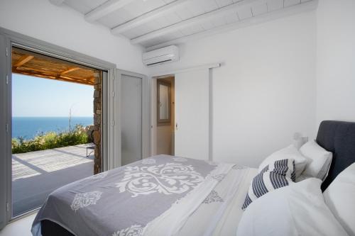 a white bedroom with a view of the ocean at Blue Sea Villa in Serifos Chora