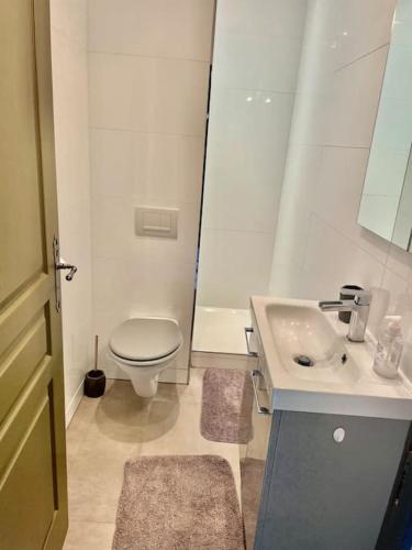 une salle de bain blanche avec des toilettes et un lavabo dans l'établissement Maison proche plages., à Benerville-sur-Mer
