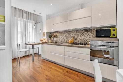 cocina con armarios blancos y mesa con microondas en Appartamento Ciliegi - Affitti Brevi Italia, en Milán