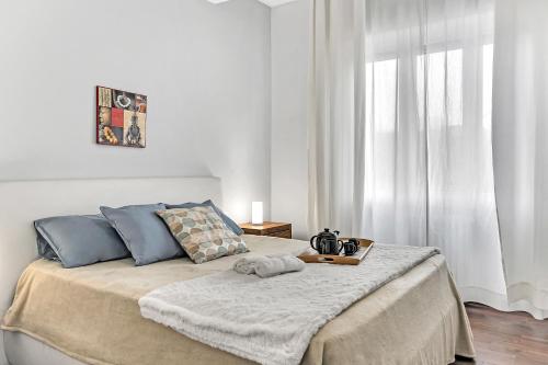 Dormitorio blanco con cama con almohadas azules en Appartamento Ciliegi - Affitti Brevi Italia, en Milán