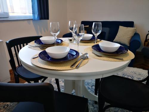 una mesa blanca con platos, tazones y copas de vino en Weisz Apartment-City Center-Free Private Parking,Wifi,Air conditioner, en Carei