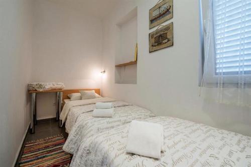 House Dubravka في كرينكا: غرفة نوم بسريرين وملاءات بيضاء ونافذة