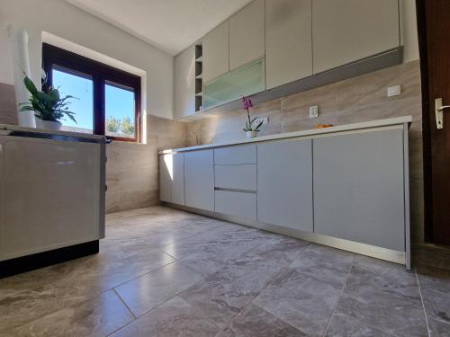 a kitchen with white cabinets and a tile floor at Apartment Dragovic in Ulcinj