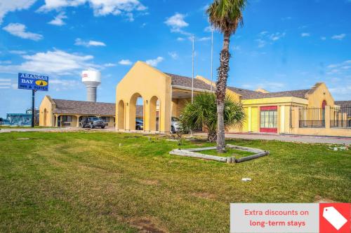 un edificio amarillo con una palmera delante en Aransas Bay Inn & Suites Corpus Christi by OYO en Aransas Pass