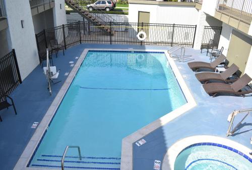 a large swimming pool with chairs and a building at Signature Anaheim Maingate in Anaheim