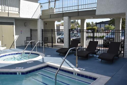 a swimming pool with chairs and a hot tub at Signature Anaheim Maingate in Anaheim