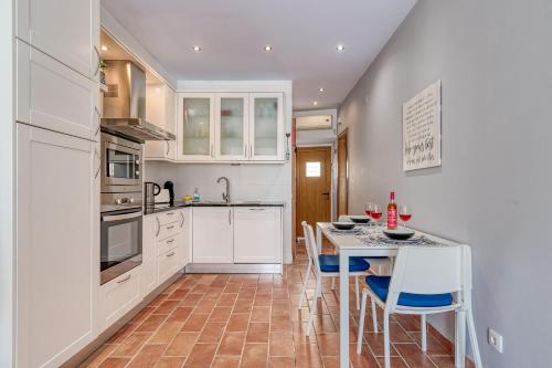 a kitchen with white cabinets and a table and chairs at Casa Perola -ocean view cottage in Carvoeiro