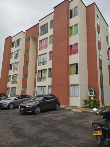 two cars parked in a parking lot in front of a building at SANDY APARTAMENTO in Santa Rosa de Cabal