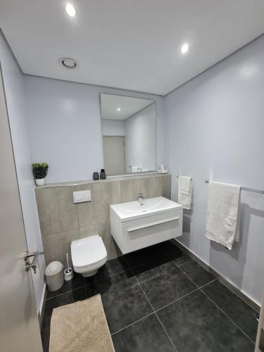 uma casa de banho com um lavatório, um WC e um espelho. em @ORRIE Apartments Infinite em Joanesburgo