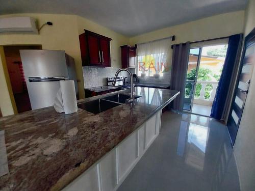 a kitchen with a counter top with a sink and a refrigerator at Highend resort in Buccoo