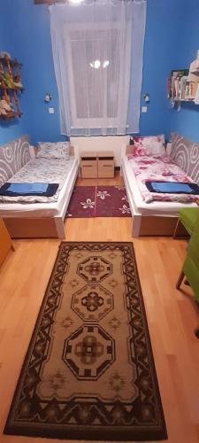 two beds in a room with a rug at Öregakác Vendégház in Tiszaladány