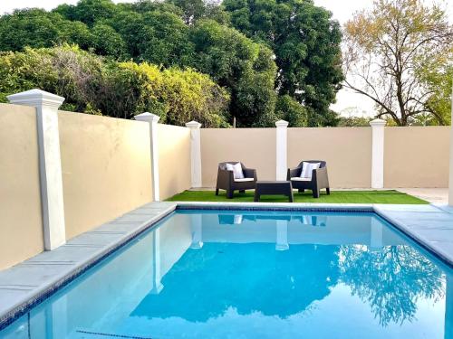 a swimming pool with two chairs next to a fence at Highend resort in Buccoo