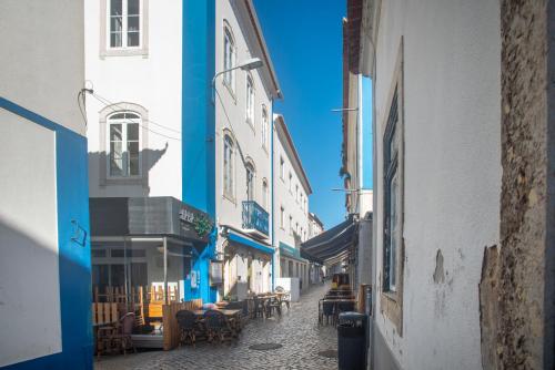 um beco com mesas e cadeiras numa rua em TikLiving na Ericeira