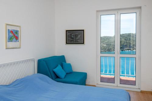 a bedroom with a blue chair and a window at Holiday Home Zaton in Dubrovnik