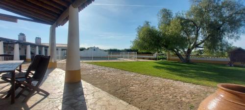 a porch of a house with a table and a yard at Montinho do Palanque in Viana do Alentejo