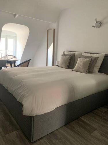 a large bed in a white room with a table at appartement catimini in Dijon