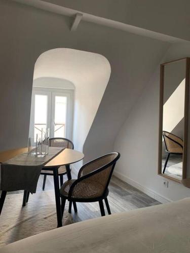 une salle à manger avec une table, des chaises et un miroir dans l'établissement appartement catimini, à Dijon