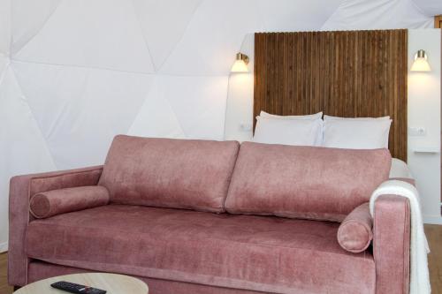 a brown couch in a room with a bed at Vi Naturae Glamping in Fajã da Ovelha