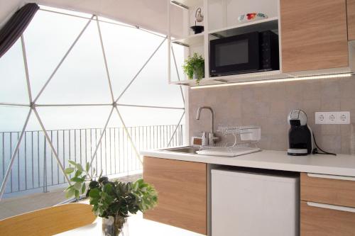 a kitchen with a sink and a large window at Vi Naturae Glamping in Fajã da Ovelha