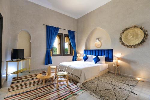 a bedroom with a bed with blue curtains and a tv at Atlas Widan in Marrakesh
