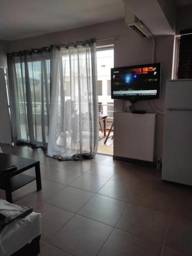 a living room with a large window and a television at Double M comfy flat in Markopoulo