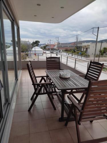 einen Holztisch und Stühle auf dem Balkon in der Unterkunft Double M comfy flat in Markopoulo