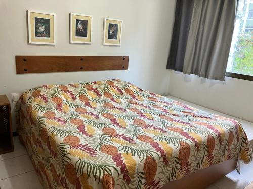 1 dormitorio con 1 cama con una manta colorida en Apart Rei Barra, en Salvador