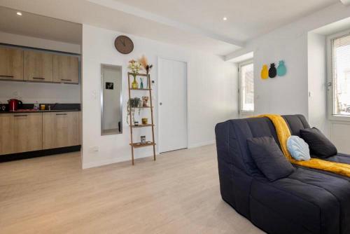 a living room with a blue couch and a kitchen at Le p’tit nid des Halles in Le Grand-Lemps