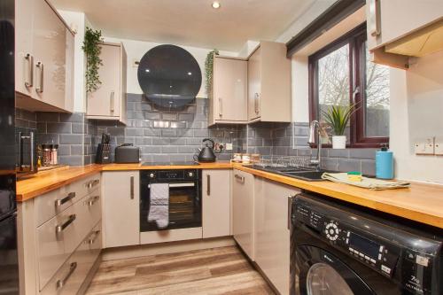 a kitchen with white cabinets and a black dishwasher at Beautiful House in Manchester Sleeps 8 Inc Parking in Wythenshawe