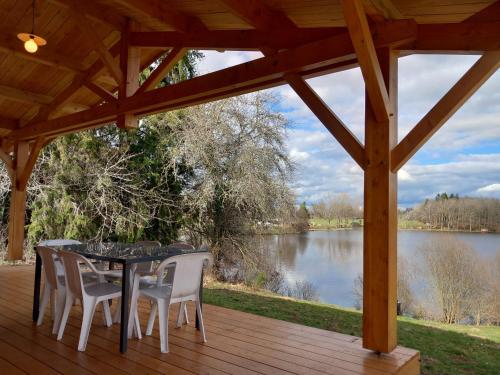 - une table et des chaises sur une terrasse avec vue sur le lac dans l'établissement Domaine du Balbuzard, à Condat-en-Combraille