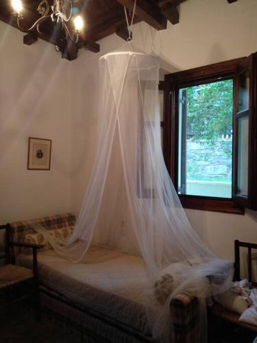 a bedroom with a bed with a mosquito net at Melina's Mansion in Tsagarada
